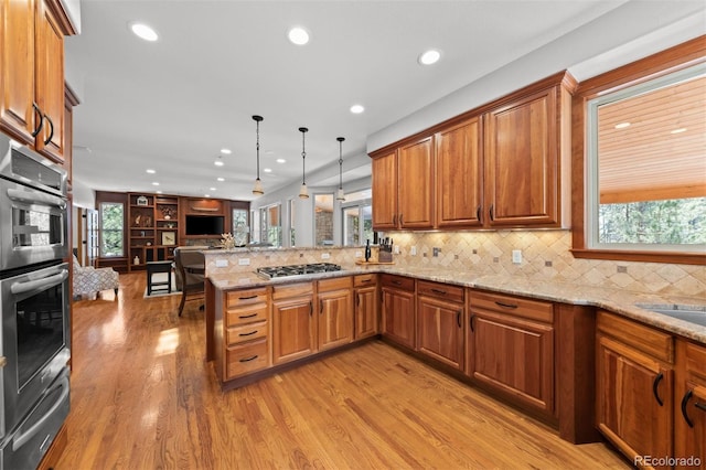 kitchen with pendant lighting, light hardwood / wood-style floors, kitchen peninsula, stainless steel appliances, and light stone countertops