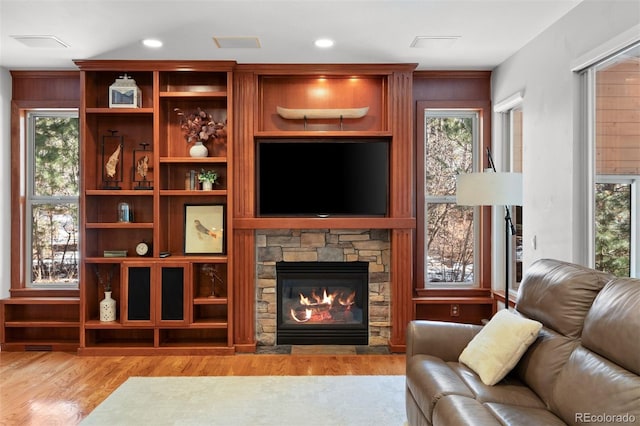 living room with a stone fireplace and light hardwood / wood-style floors