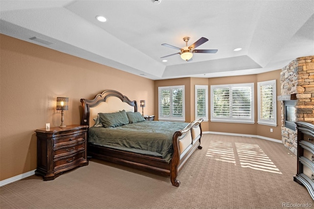 bedroom with a raised ceiling, light carpet, and ceiling fan