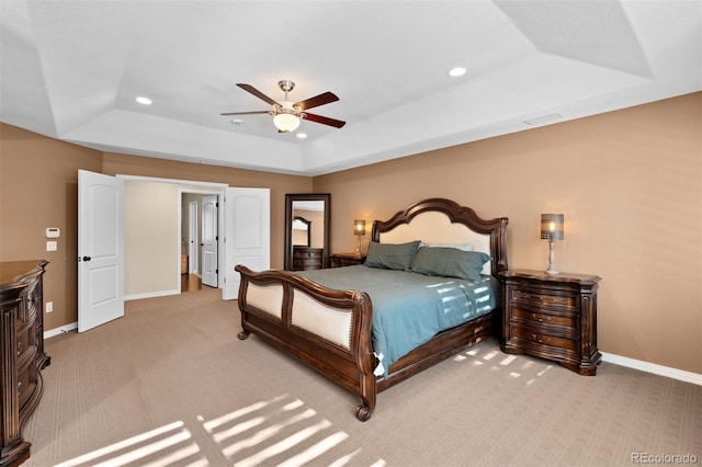 carpeted bedroom with a raised ceiling and ceiling fan