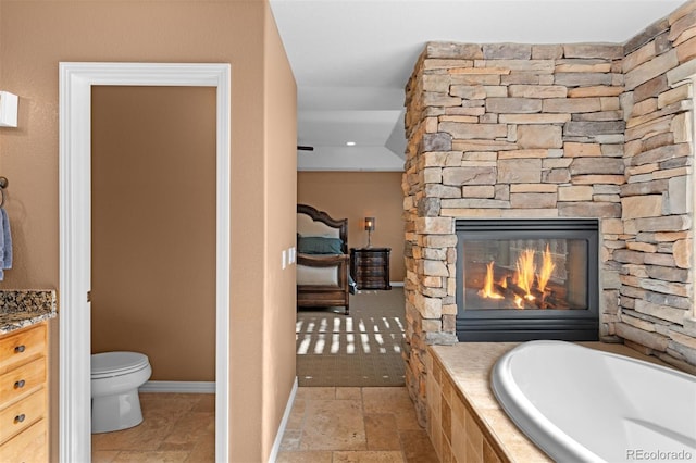 bathroom with vanity, a bath, a fireplace, and toilet