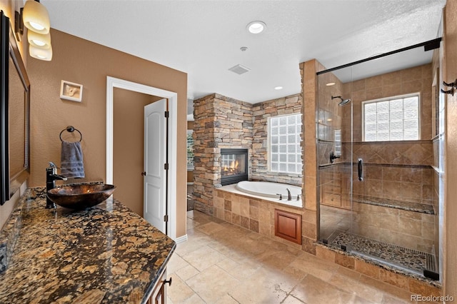 bathroom with a fireplace, plus walk in shower, sink, and a textured ceiling