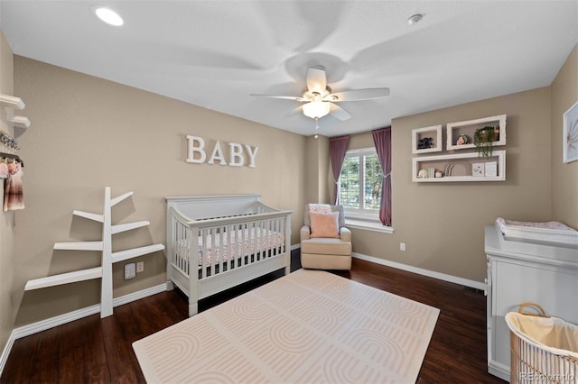 bedroom with ceiling fan, dark hardwood / wood-style flooring, and a crib