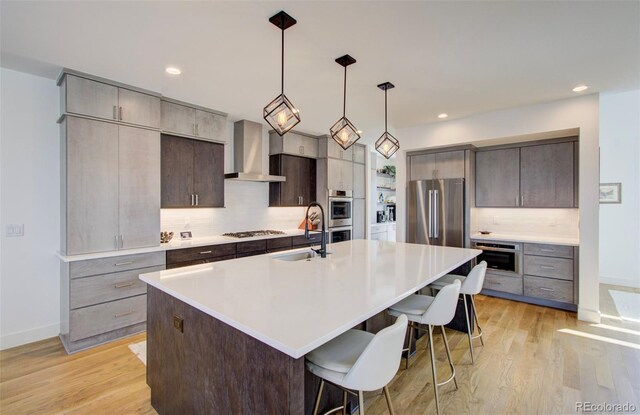 4224 E Dickenson Pl, Denver, CO 80222 - kitchen with wall chimney exhaust hood, appliances with stainless steel finishes, decorative backsplash, light countertops, and a breakfast bar area