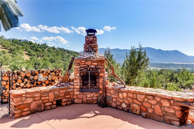 view of patio with a mountain view and an outdoor stone fireplace