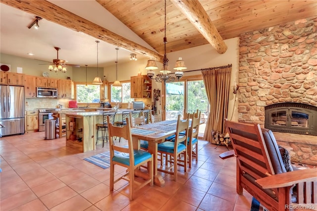 dining space featuring light tile patterned floors, lofted ceiling with beams, a fireplace, wooden ceiling, and ceiling fan with notable chandelier