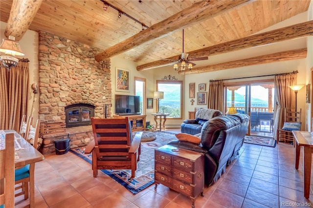 tiled living room with wood ceiling, rail lighting, vaulted ceiling with beams, a stone fireplace, and ceiling fan