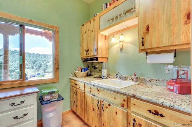 kitchen with light brown cabinetry, light tile patterned flooring, and a sink