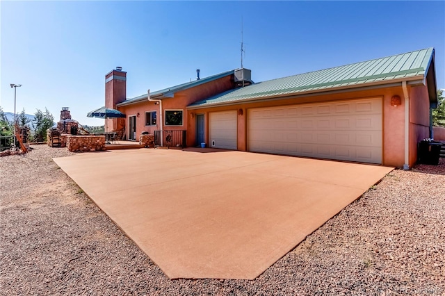 view of front facade featuring stucco siding, cooling unit, metal roof, concrete driveway, and a garage