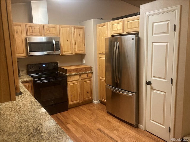 kitchen with light stone counters, light brown cabinetry, stainless steel appliances, and light hardwood / wood-style floors