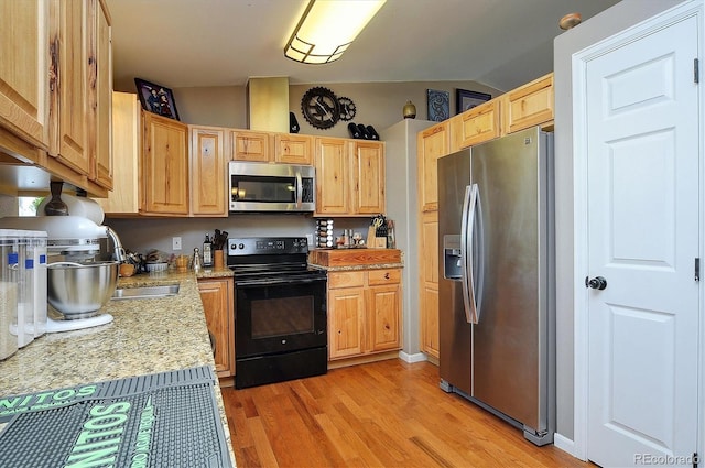 kitchen featuring lofted ceiling, light brown cabinetry, stainless steel appliances, and light hardwood / wood-style floors