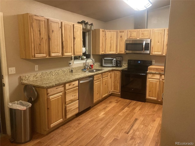 kitchen featuring appliances with stainless steel finishes, sink, light hardwood / wood-style floors, light stone countertops, and light brown cabinets