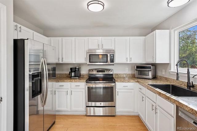 104 Willowick Cir, Highlands Ranch, CO 80129 - kitchen featuring stainless steel appliances, white cabinets, light wood-style flooring, and tile counters