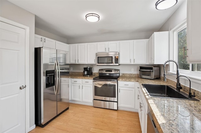 104 Willowick Cir, Highlands Ranch, CO 80129 - kitchen featuring stainless steel appliances, white cabinets, light wood-type flooring, and light stone counters