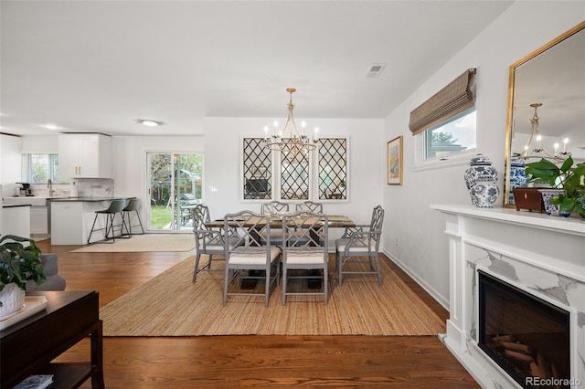 986 S Jersey St, Denver, CO 80224 - dining area with a chandelier, dark wood-style flooring, healthy amount of natural light, and a high end fireplace