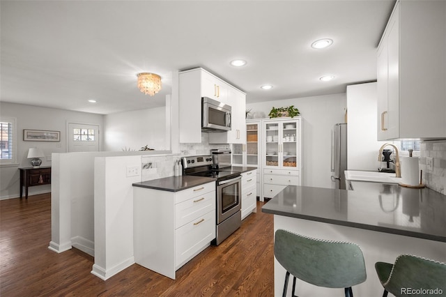 986 S Jersey St, Denver, CO 80224 - kitchen with appliances with stainless steel finishes, a peninsula, a sink, dark countertops, and recessed lighting