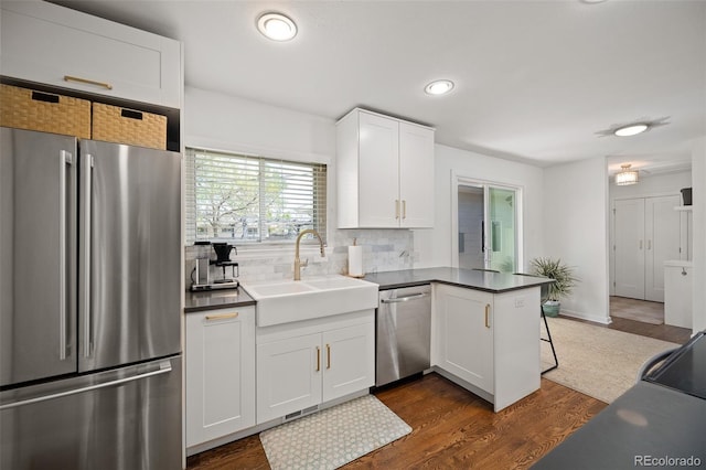 986 S Jersey St, Denver, CO 80224 - kitchen featuring appliances with stainless steel finishes, a sink, a peninsula, recessed lighting, and dark wood-style floors
