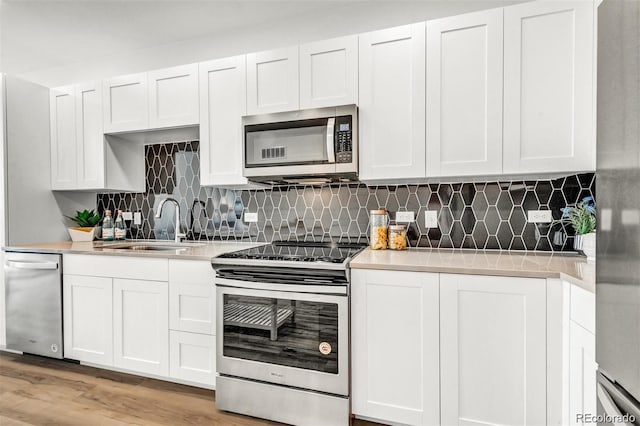 kitchen featuring sink, white cabinetry, stainless steel appliances, and light hardwood / wood-style flooring