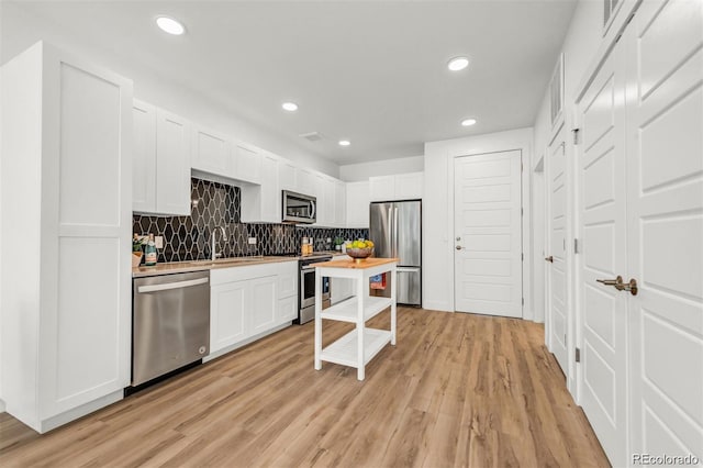 kitchen featuring wood counters, appliances with stainless steel finishes, sink, and white cabinets