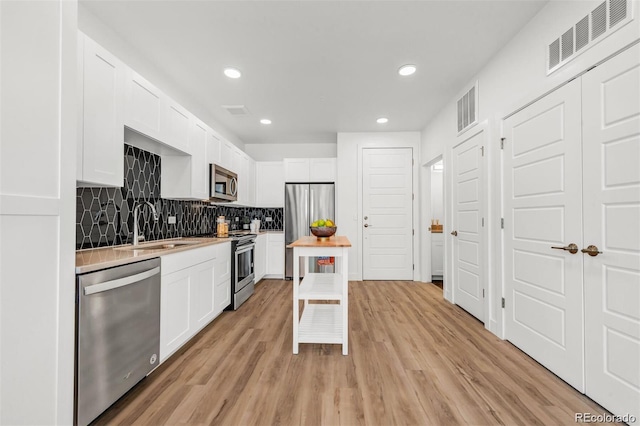 kitchen featuring stainless steel appliances, white cabinetry, sink, and light wood-type flooring