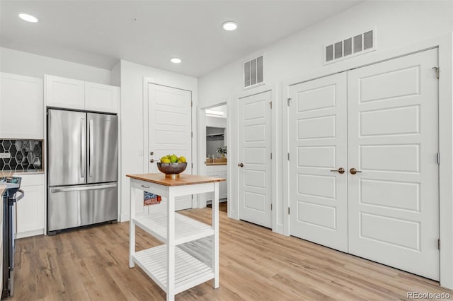 kitchen with white cabinetry, tasteful backsplash, stainless steel appliances, and light hardwood / wood-style floors