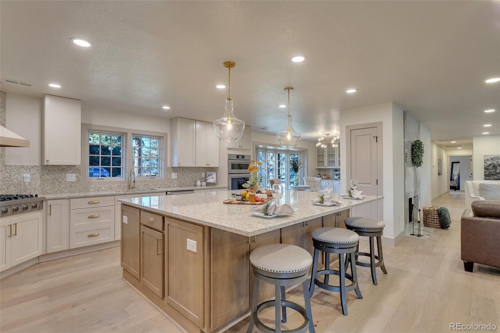 kitchen with white cabinetry, a spacious island, and light hardwood / wood-style floors