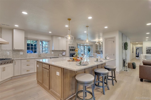 kitchen with white cabinetry, a spacious island, and light hardwood / wood-style floors