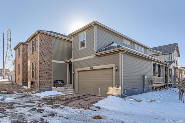 snow covered property with a garage