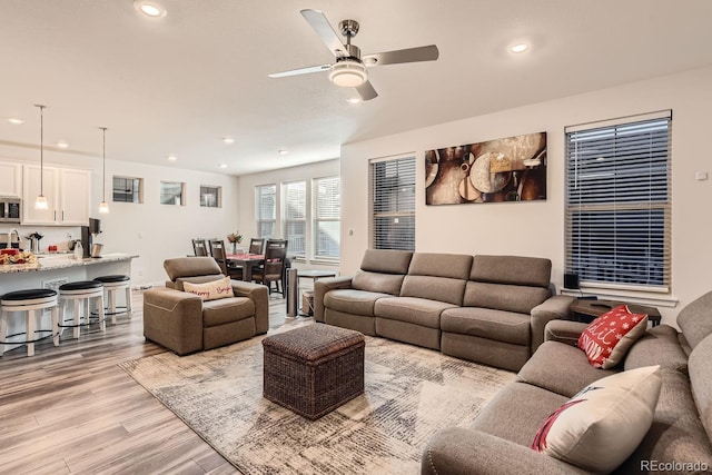 living room with ceiling fan and light hardwood / wood-style flooring