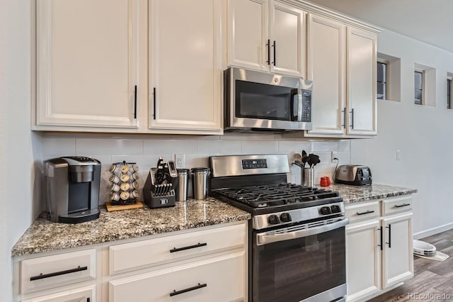 kitchen with light stone counters, decorative backsplash, white cabinets, and appliances with stainless steel finishes