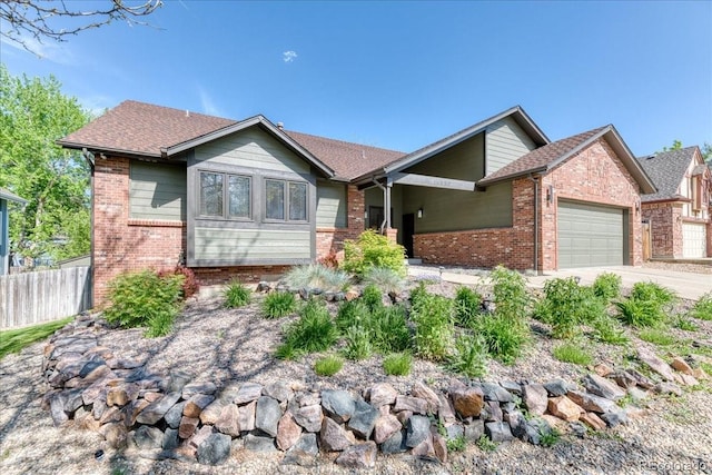 view of front of property featuring brick siding, fence, a garage, driveway, and a shingled roof