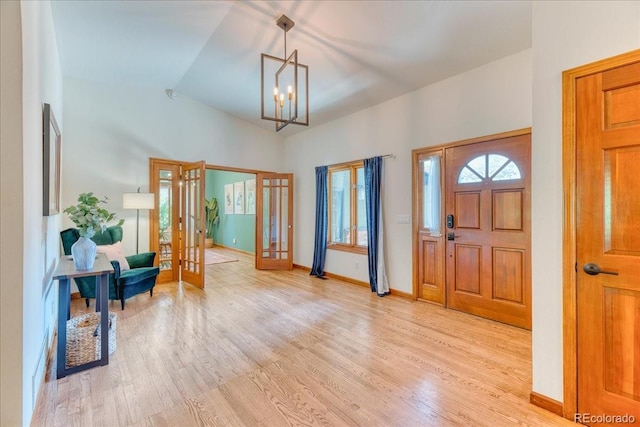 entrance foyer with light wood finished floors, a chandelier, french doors, baseboards, and vaulted ceiling