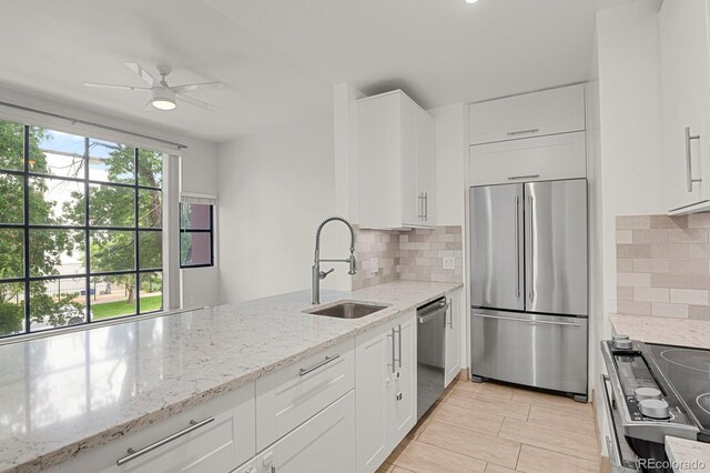 505 E 24th St Unit 204, Denver, CO 80205 - kitchen featuring stainless steel appliances, backsplash, white cabinets, light stone countertops, and a ceiling fan