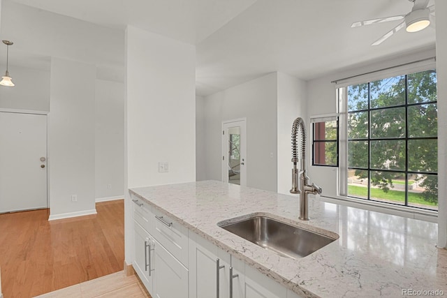 505 E 24th St Unit 204, Denver, CO 80205 - kitchen featuring white cabinets, ceiling fan, light stone countertops, hanging light fixtures, and light wood finished floors