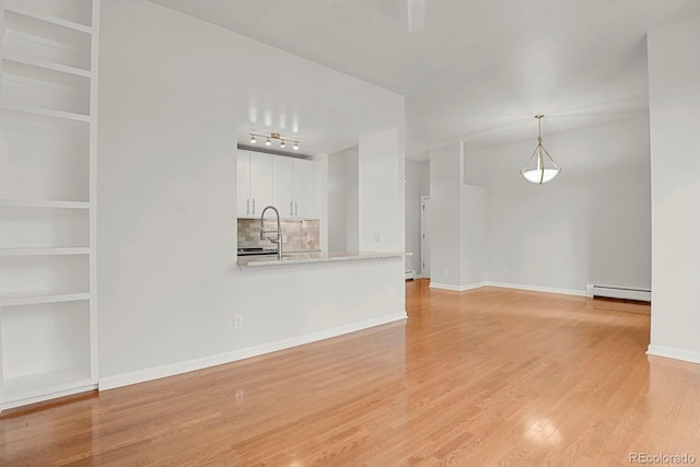 505 E 24th St Unit 204, Denver, CO 80205 - unfurnished living room featuring baseboard heating, light wood-type flooring, and a baseboard radiator