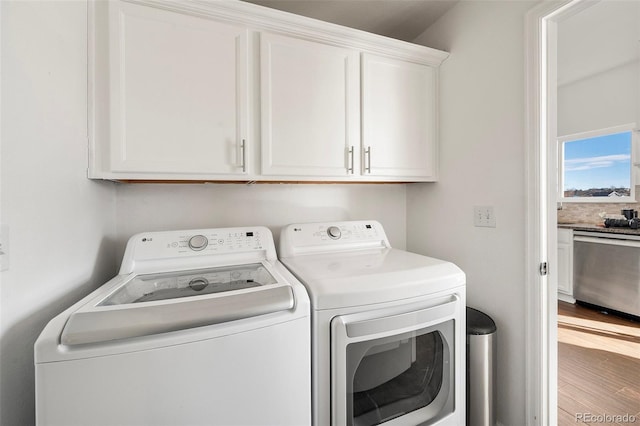 laundry room with hardwood / wood-style flooring, separate washer and dryer, and cabinets