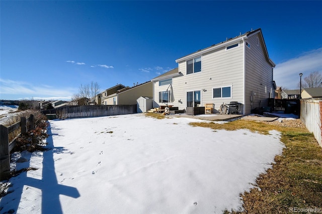 snow covered property featuring a patio area and a shed