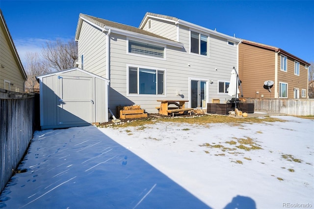 snow covered back of property featuring central AC unit and a shed