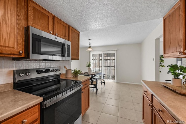 1280 Sable Blvd, Aurora, CO 80011 - kitchen featuring stainless steel appliances, backsplash, light tile patterned floors, baseboards, and brown cabinetry