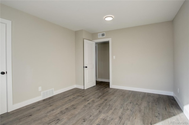 spare room featuring visible vents, baseboards, and wood finished floors