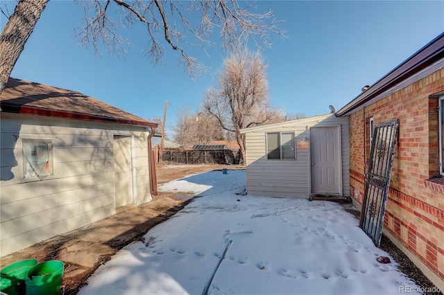 yard covered in snow with an outdoor structure and fence