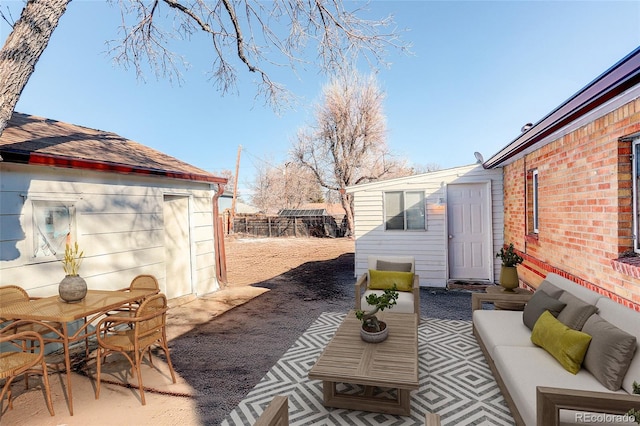 view of patio featuring outdoor dining area, an outdoor structure, fence, and an outdoor hangout area