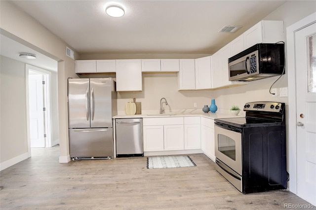 kitchen with visible vents, appliances with stainless steel finishes, white cabinets, and a sink