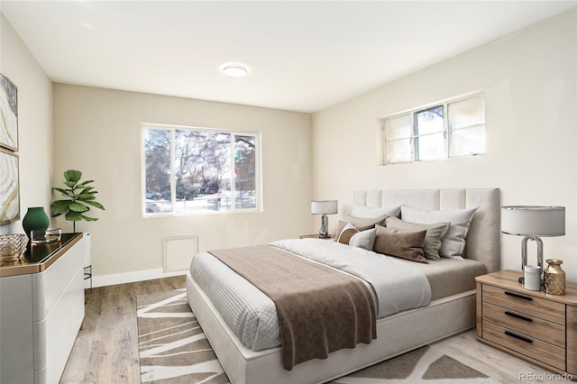 bedroom featuring baseboards, multiple windows, and light wood-style floors