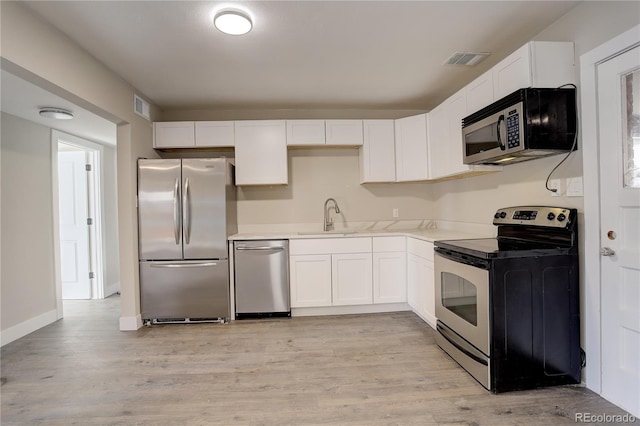 kitchen featuring stainless steel appliances, a sink, visible vents, and white cabinetry