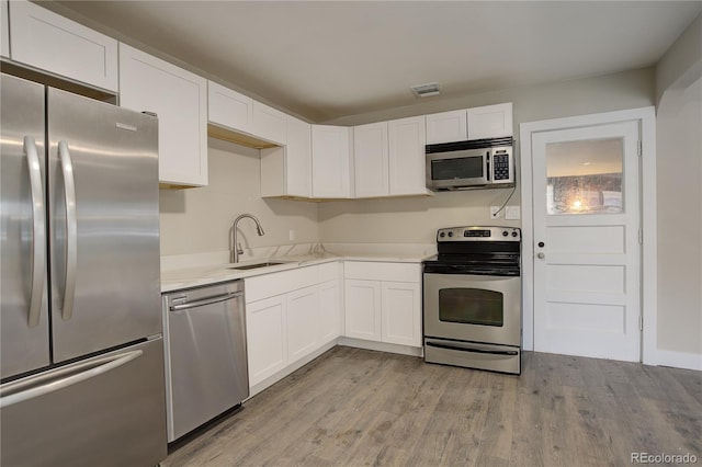 kitchen featuring white cabinets, stainless steel appliances, a sink, and light countertops