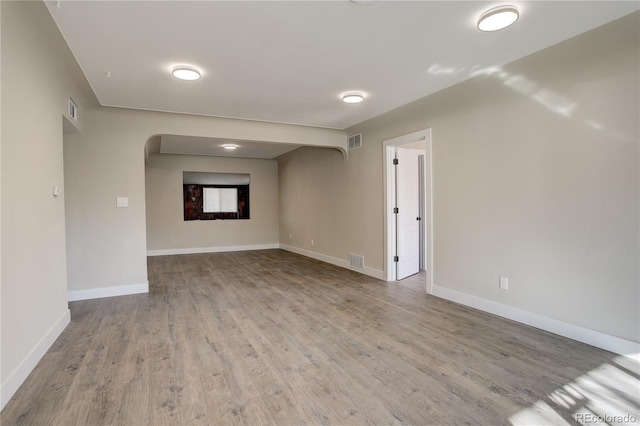 spare room with wood finished floors, visible vents, and baseboards