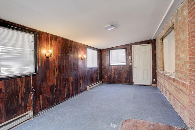 carpeted empty room featuring a baseboard heating unit and wood walls