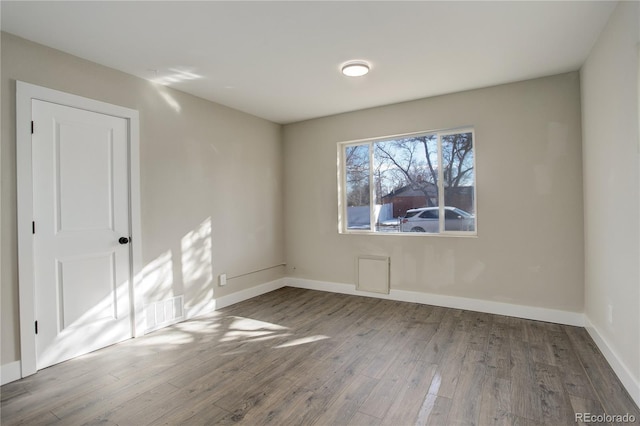 spare room with visible vents, baseboards, and wood finished floors