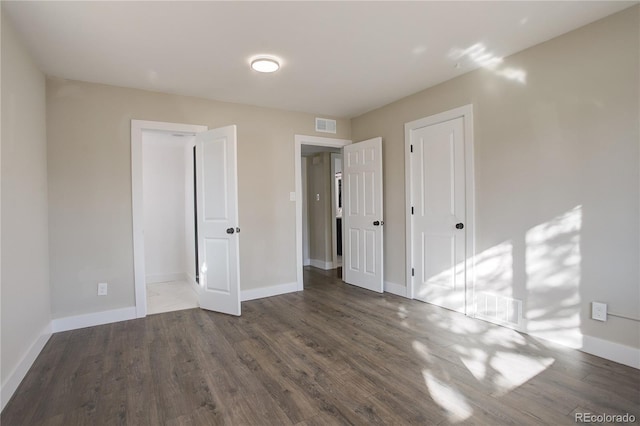 unfurnished bedroom with visible vents, baseboards, and wood finished floors